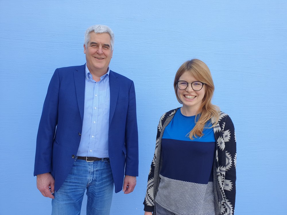 Bild: Die Kreisrät*innen Marlene Schönberger und Martin Schachtl vor einer weißen Wand.